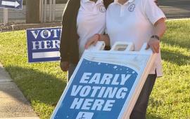 Election workers with early voting here sign.