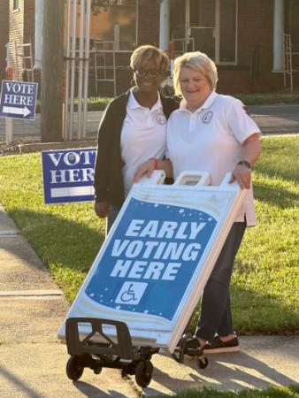 Election workers with early voting here sign.