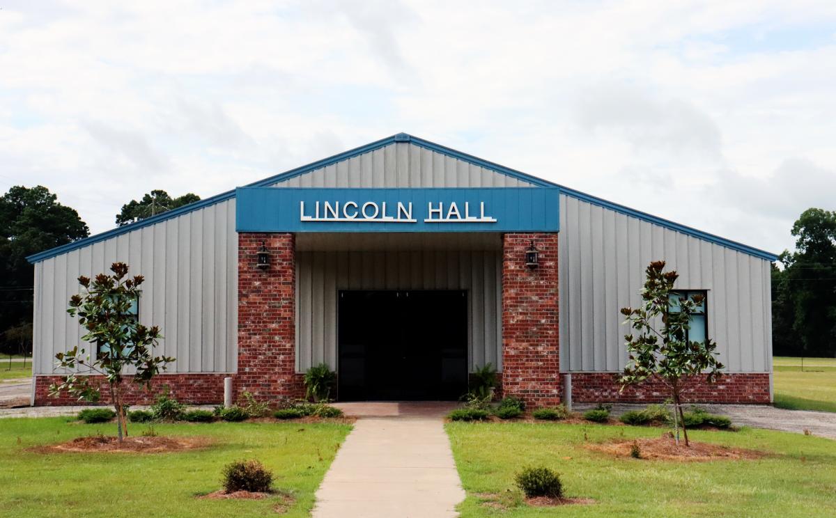 Exterior image of metal building with brick columns and blue awning